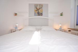 um quarto com uma grande cama branca e 2 candeeiros em Haus Marienfeld Wohnung "Marla" em Grömitz