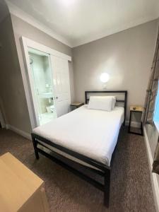 een slaapkamer met een groot wit bed en een raam bij Lords Hotel in Londen