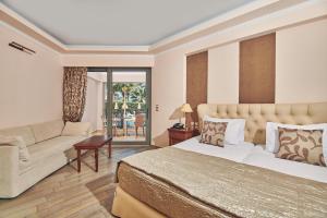 Palazetto Suites Zakynthos - Adults Only في تسيليفي: غرفه فندقيه بسرير واريكه