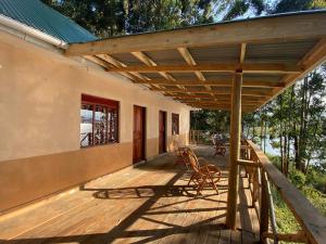 Itambira Island, Seeds of Hope في Chabahinga: سطح خشبي مع شمسية على منزل
