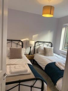 a bedroom with two beds and a lamp and a window at Broadstairs Beach Bungalow. Dogs welcome! in Broadstairs