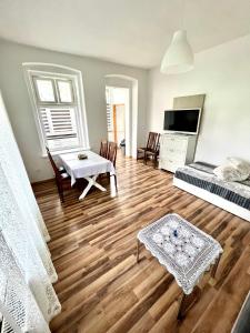 una sala de estar con suelo de madera y una habitación con mesa en Apartament Willa Aurora, en Kudowa-Zdrój