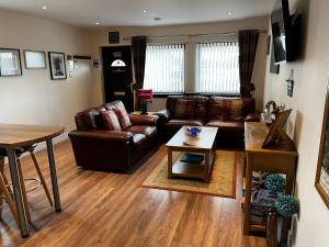a living room with a leather couch and a table at Lesanne Cottage in Inverness