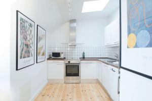a kitchen with white cabinets and a wooden floor at Cozy 3BR Lake View Flat w Bath Tub in Copenhagen in Copenhagen