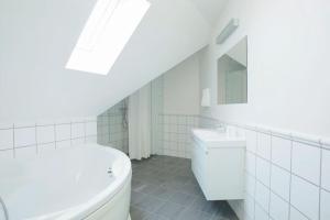 a white bathroom with a tub and a sink at Cozy 3BR Lake View Flat w Bath Tub in Copenhagen in Copenhagen