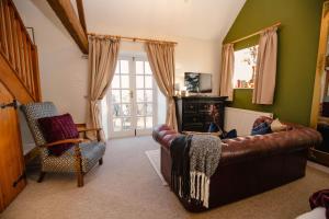a living room with a leather couch and a chair at Hayloft Cottage - Rudge Farm Cottages in Bridport
