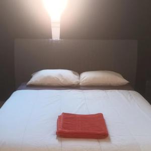 Una cama con dos almohadas y una toalla roja. en Apartamento en Castellón RENFE, en Castellón de la Plana