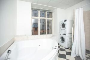 La salle de bains blanche est pourvue d'une baignoire et d'un lave-linge. dans l'établissement Large & Bright 3BR Flat w Whirlpool Near Metro, à Copenhague