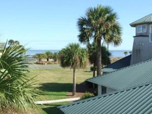 a house with palm trees next to a building at JEKYLL KEEPERS QUARTERS apts in Jekyll Island