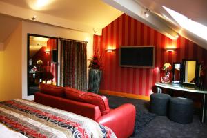 een rode kamer met een bank en een televisie bij Gibbon Bridge Hotel in Clitheroe