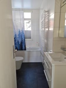 a bathroom with a tub and a toilet and a sink at Appartement au centre du village 4-6 personnes in Leysin