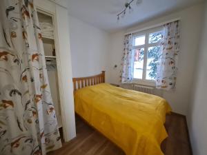 a bedroom with a yellow bed and a window at Appartement au centre du village 4-6 personnes in Leysin