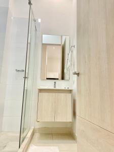 y baño con ducha, lavabo y espejo. en Apartamentos Loft Mikonos, en Pereira