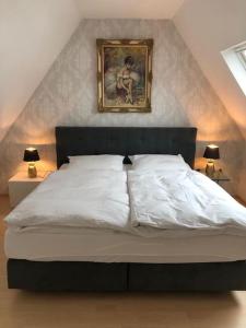 a bedroom with a white bed with a painting on the wall at Superschöne Ferienwohnungen! in Buxheim