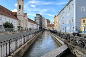 a river in the middle of a city with buildings at Cozy City Center Apartment in Graz