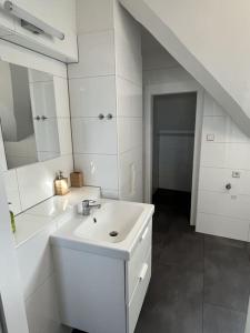 a white bathroom with a sink and a mirror at Cozy City Center Apartment in Graz