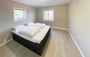 a large bed in a room with two windows at 4 Bedroom Beautiful Apartment In Herdla in Herlø