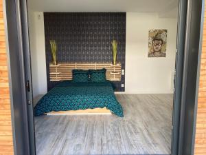 1 dormitorio con 1 cama con manta azul y almohadas en Adorable Studio d'hôte zen et paisible, en Les Gonds