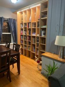 ein Esszimmer mit einem Tisch und einem Bücherregal in der Unterkunft Wonderful 2 Bedroom in the heart of Astoria in Steinway