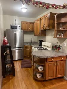 eine Küche mit einem Kühlschrank aus Edelstahl und Holzschränken in der Unterkunft Wonderful 2 Bedroom in the heart of Astoria in Steinway