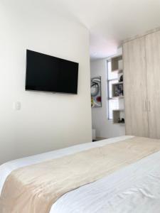 1 dormitorio con 1 cama y TV de pantalla plana en la pared en Apartamentos Loft Mikonos, en Pereira
