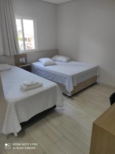 um quarto com 2 camas e uma janela em Hotel Serrano em Frederico Westphalen