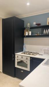 a kitchen with a stove and a black refrigerator at T&L Apartments Germasogia in Limassol