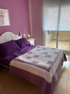 1 dormitorio con 1 cama con pared morada en APARTAMENTO PALMERAL DEL MAR MENOR, en Los Nietos
