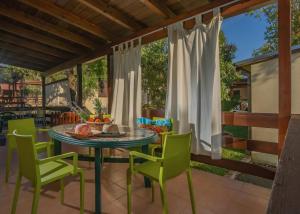 a patio with a table and green chairs at Villaggio Leucosia in Santa Maria di Castellabate