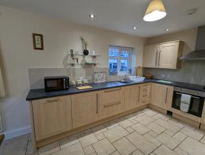 a kitchen with wooden cabinets and a black counter top at Unbeatable Llanberis Location, Detached with Parking, Snowdon Views. in Llanberis