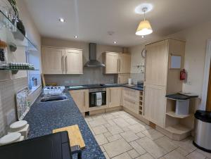 a large kitchen with wooden cabinets and appliances at Unbeatable Llanberis Location, Detached with Parking, Snowdon Views. in Llanberis