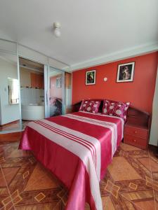 1 dormitorio con 1 cama grande y paredes rojas en Hostal Bryan en Tacna