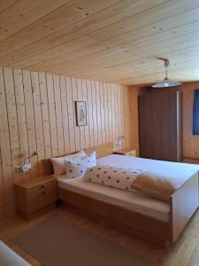 a bedroom with a large bed and wooden walls at Haus Annelies in Bizau