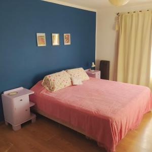1 dormitorio con 1 cama con colcha roja y pared azul en JuMei en Chascomús