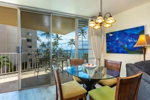 a living room with a table and chairs and a balcony at Kamaole Nalu 402 condo in Kihei