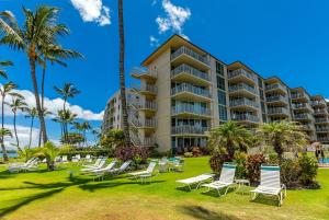 a resort with chairs and palm trees on a lawn at Kamaole Nalu 402 condo in Kihei