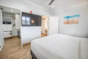 a white bedroom with a bed and a tv at Hotel SOL in St Pete Beach