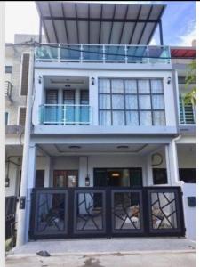 a white house with black doors and a balcony at Aisyah homestay islam shj in Tanah Merah