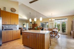 cocina con armarios de madera y comedor en Big Island Awamoa Hale home, en Waikoloa