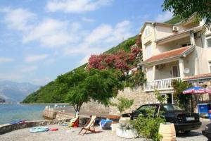 a house with a car parked next to the water at Apartmani Vesna in Tivat