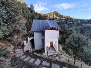 una pequeña casa con techo de metal en una colina en Ziran retreat en Mukteswar