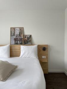 a large white bed with two pictures on the headboard at Hotel restaurant SAM in Tholen