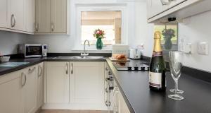 a kitchen with a bottle of champagne and a wine glass at Sandpiper 3 - The Cove - Stunning views, Heated Pool, Allocated Parking in Brixham