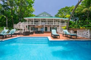 a swimming pool with chairs and a house at Serenity Beach Home in West End