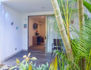 un couloir avec une porte s'ouvrant sur une pièce ornée de plantes dans l'établissement La Vela Boutique Hotel, à Manuel Antonio