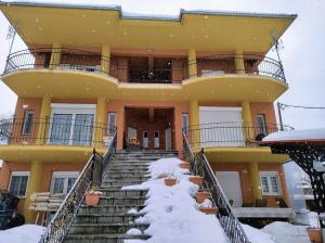 Lávdhas的住宿－Cozy cottage for 4，前面的楼梯上积雪的建筑