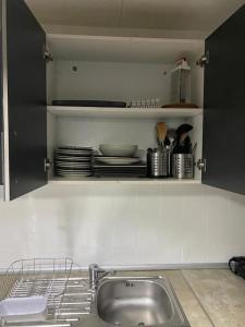 una cocina con fregadero y un estante con platos en Appartement Célia, en Algemesí