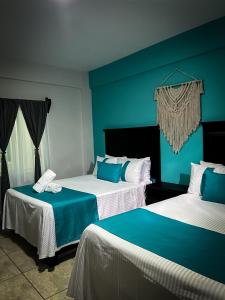 two beds in a room with blue and white at Hotel Tamtokow in Ciudad Valles