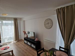 a living room with a television and a clock on the wall at Star Airport Residence in Otopeni