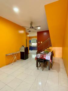 uma sala de jantar com uma mesa e paredes amarelas em DeSyafiq Homestay em Kuala Kedah